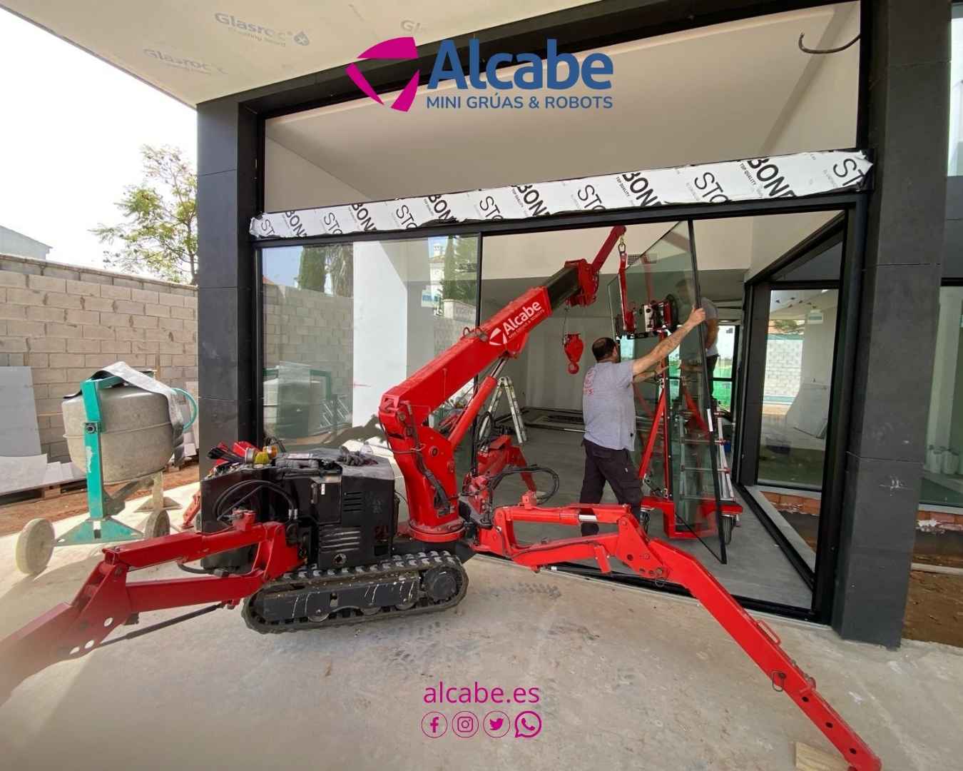 Mini grúa colocando cristales de gran envergadura en Urbanización La Juliana, en Bollullos de la Mitación, en Sevilla.