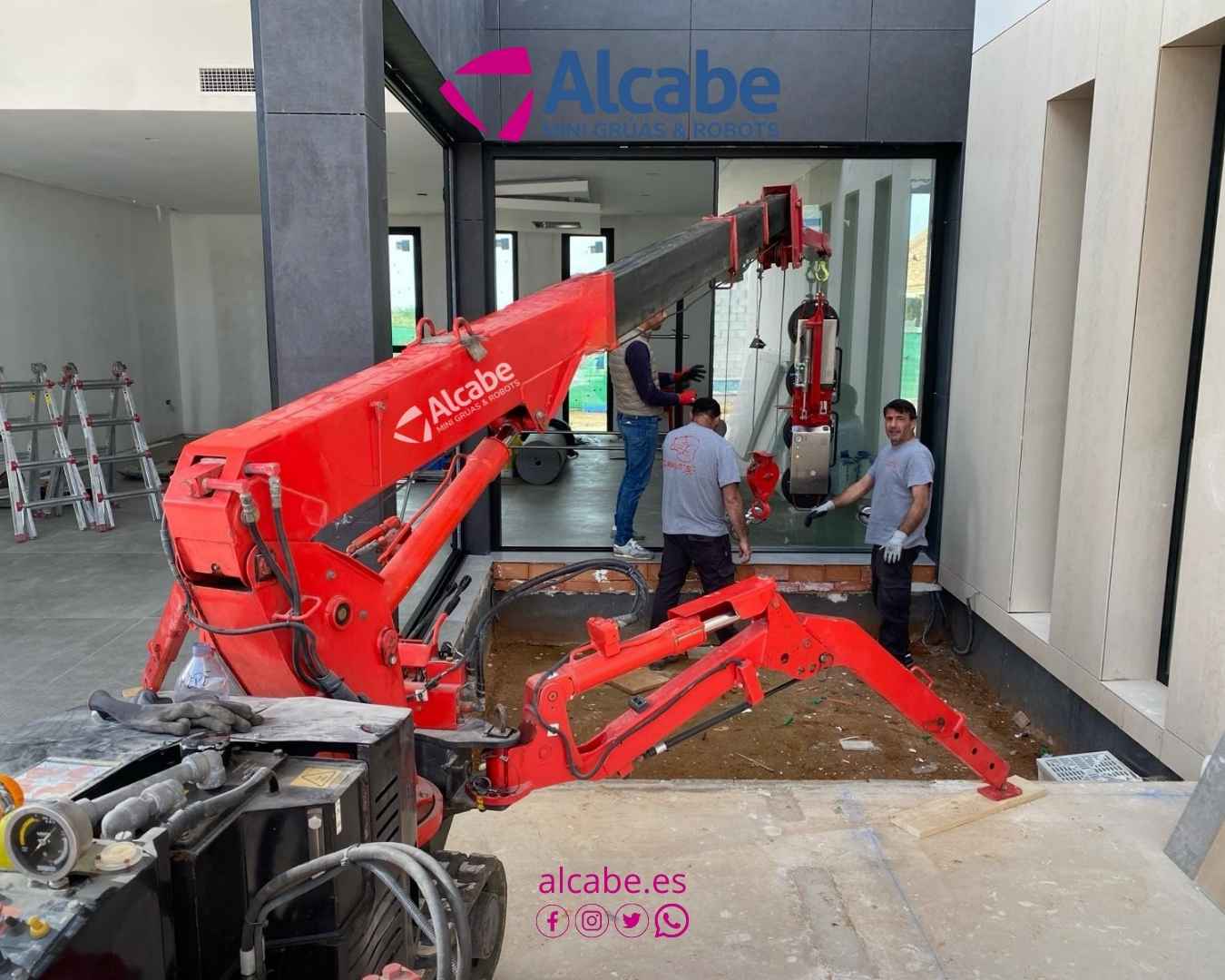 Mini grúa colocando cristales de gran envergadura en Urbanización La Juliana, en Bollullos de la Mitación, en Sevilla.