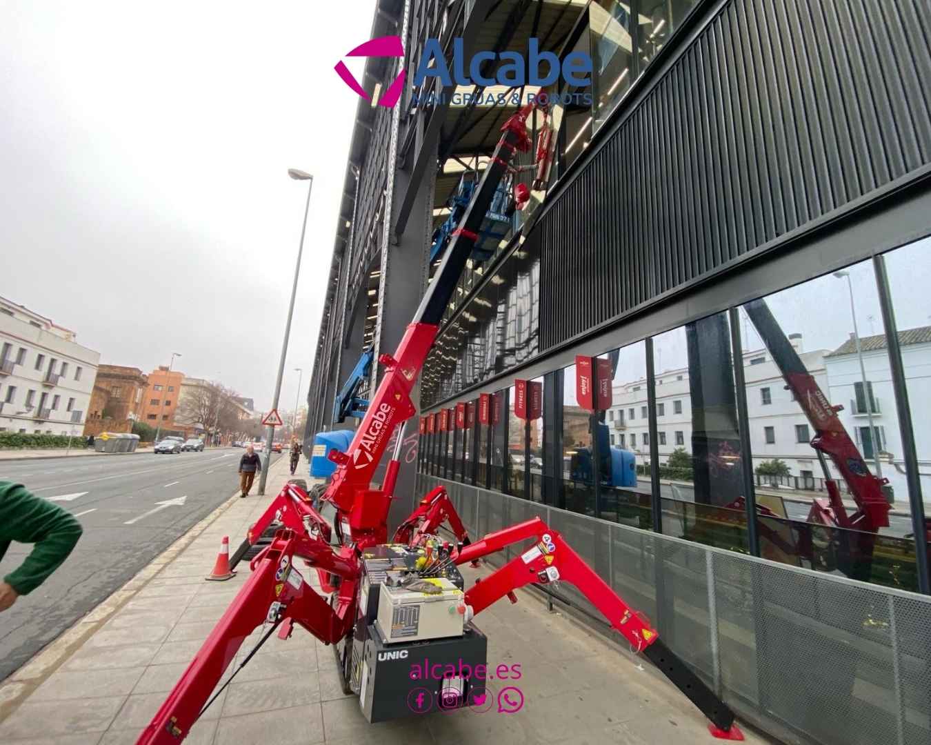 Mini grúa alquilada a ALCABE para la colocación de escaparate y vidriera exterior de toda la fachada del gimnasio Enjoy San Bernardo, en Sevilla