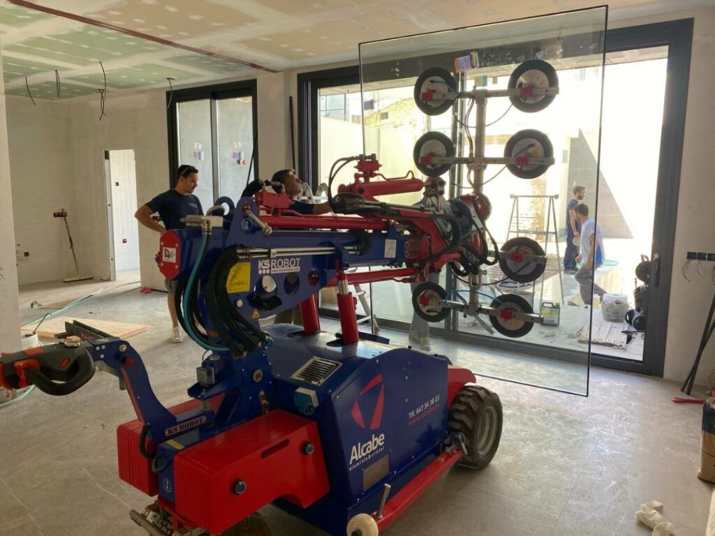 Movimiento e instalación de cristales para el cerramiento del salón hacia el jardín, de este chalet en Herrera, Sevilla.